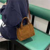 Vintage corduroy handbag with adjustable strap on woman, ideal for casual outings.