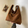 Vintage suede shoulder bag with adjustable strap and interior pockets, women's fashion accessory.