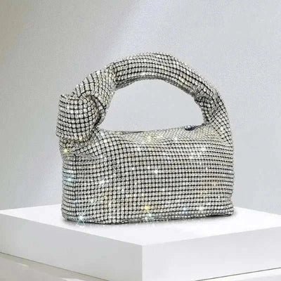 Luxury silver rhinestone knot handle evening bag on display.